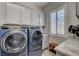 Well-lit laundry room featuring a front-load washer/dryer set, granite counters, and ample cabinet space above the appliances at 7095 Falabella Ridge Ave, Las Vegas, NV 89131