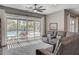 Bright living room with a gray sectional couch, ceiling fan, and sliding doors leading to the backyard pool and patio at 7095 Falabella Ridge Ave, Las Vegas, NV 89131