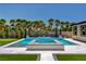 Lush backyard with a pool, hot tub, manicured green spaces, and mature palm trees at 7095 Falabella Ridge Ave, Las Vegas, NV 89131