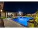 Luxurious backyard with a sparkling swimming pool, spa, and lush landscaping, illuminated at night at 7095 Falabella Ridge Ave, Las Vegas, NV 89131