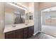 Bathroom featuring double sinks, dark wood cabinets, and a view of the walk in shower at 7116 Wonderberry St, Las Vegas, NV 89131