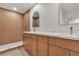 Modern bathroom with double vanity, wood cabinets, and a walk-in shower with wood-look tile at 8537 Glenmount Dr, Las Vegas, NV 89134