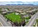 Wide aerial shot showcasing a park with green fields and sports courts, surrounded by a community of homes at 9921 Rams Leap Ave, Las Vegas, NV 89166