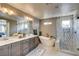 Modern bathroom featuring a soaking tub, dual sinks, and walk-in shower with a glass door at 9921 Rams Leap Ave, Las Vegas, NV 89166