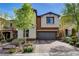 Two-story home with a well-manicured front yard and an attached two-car garage and brick driveway at 9921 Rams Leap Ave, Las Vegas, NV 89166