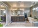 Well lit main bathroom features a dual sink vanity, stand alone tub, and glass enclosed shower at 9921 Rams Leap Ave, Las Vegas, NV 89166