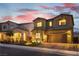 Beautiful two-story home featuring a two-car garage, stone accents, and well-manicured landscaping at dusk at 10372 Thurso Ave, Las Vegas, NV 89166