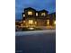 Night shot of a modern two-story stucco home with brick driveway and exterior lighting at 10372 Thurso Ave, Las Vegas, NV 89166
