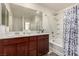 Clean bathroom featuring double sinks, a large mirror, and a shower-tub combo with patterned curtain at 105 Pollentia Ave, North Las Vegas, NV 89084