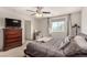 Comfortable bedroom with a plush bed, ceiling fan, and a classic wooden dresser with TV at 105 Pollentia Ave, North Las Vegas, NV 89084