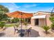 Backyard with patio, lounge chairs, lush landscaping, and desert surroundings under a blue sky at 10581 Santo Marco Ct, Las Vegas, NV 89135