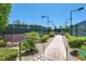 A tennis court surrounded by gravel, vegetation, and green fencing at 10581 Santo Marco Ct, Las Vegas, NV 89135
