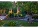 Lush backyard featuring decorative lighting, art, and a retaining wall surrounded by mature trees at 11037 Clarion Ln, Las Vegas, NV 89134