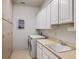 Functional laundry room with washer, dryer, storage cabinets, sink, and tile floors at 11037 Clarion Ln, Las Vegas, NV 89134