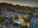 Aerial view of a luxurious home showcasing an illuminated pool and the mountain views at 11573 Glowing Sunset Ln, Las Vegas, NV 89135