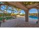Relaxing back patio with vine-covered pergola, outdoor kitchen, and sparkling pool views at 11573 Glowing Sunset Ln, Las Vegas, NV 89135