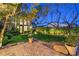 Serene backyard featuring lush lawn, mature trees, and a charming brick patio at 11573 Glowing Sunset Ln, Las Vegas, NV 89135