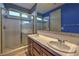 Bright bathroom with a shower, dual sinks and vanities, and blue accent wall at 11573 Glowing Sunset Ln, Las Vegas, NV 89135