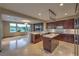 Spacious kitchen featuring dark wood cabinets, central island, stone countertops and modern lighting fixtures at 11573 Glowing Sunset Ln, Las Vegas, NV 89135