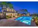 Beautifully illuminated pool and spa area with lush landscaping, complemented by the home's elegant architecture at 11573 Glowing Sunset Ln, Las Vegas, NV 89135