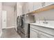 Modern laundry room with sink, gray cabinetry, and stainless steel washer and dryer at 11870 Tevare Ln # 1085, Las Vegas, NV 89138