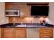 Modern kitchenette featuring sleek countertops, wooden cabinetry, microwave, refrigerator and a built-in television at 135 E Harmon Ave # 3215, Las Vegas, NV 89109