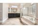 Bright bathroom featuring a soaking tub with glass block window and black dual vanities at 1779 Sebring Hills Dr, Henderson, NV 89052