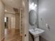 A downstairs bathroom with an oval mirror hangs above a pedestal sink on a wood floor at 2767 Flowing Breeze St, Henderson, NV 89044