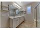 Bright bathroom with double sinks, quartz counters, decor shelves and a glass shower with a tiled floor at 2767 Flowing Breeze St, Henderson, NV 89044