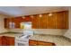 A traditional kitchen featuring granite countertops, wooden cabinets, and white appliances at 3820 Ice Storm Ct, Las Vegas, NV 89129