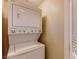A compact, stacked white washer and dryer unit in a laundry closet with a shelf at 3820 Ice Storm Ct, Las Vegas, NV 89129