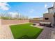 Backyard featuring artificial grass, gravel, and a patio seating area at 7132 Sayonara Vista St, North Las Vegas, NV 89084
