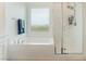 Bathroom featuring large tub, glass-enclosed shower and window for natural light at 7132 Sayonara Vista St, North Las Vegas, NV 89084