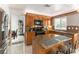 Well-lit kitchen featuring a breakfast bar, granite countertops, stainless steel refrigerator, and wooden cabinetry at 730 Rusty Spur Dr, Henderson, NV 89014