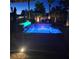 Backyard swimming pool with LED lights, lush tropical plants, and mature trees under a starlit sky at 8209 Chapelle Ct, Las Vegas, NV 89131