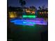 A backyard pool and waterfall feature illuminated by color-changing LED lights offers a relaxing outdoor retreat at night at 8209 Chapelle Ct, Las Vegas, NV 89131