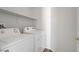 Well-lit laundry area with white washer and dryer, and ample shelving space at 830 Binbrook Dr, Henderson, NV 89052