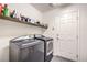Laundry room with modern gray washer and dryer set, storage shelf, and access door at 8454 Mondavi Hill Ct, Las Vegas, NV 89139