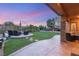 Expansive backyard featuring a manicured lawn, mature trees, patio with stone pillars and stylish seating at 9 Contra Costa Pl, Henderson, NV 89052