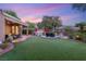 Backyard featuring a covered patio, outdoor kitchen, and artificial grass at 9 Contra Costa Pl, Henderson, NV 89052
