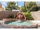 A luxurious rock waterfall flows into a serene pool, creating a tranquil backyard oasis at 9416 Rolling Ridge Ln, Las Vegas, NV 89134