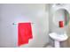 Simple half bathroom featuring a pedestal sink, round mirror, and a colorful red towel on a silver rack at 9879 Jazzy June St, Las Vegas, NV 89183