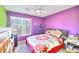 Cozy bedroom featuring purple walls, a ceiling fan, and a comfortable bed with colorful bedding at 9879 Jazzy June St, Las Vegas, NV 89183