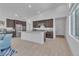 Open-concept kitchen featuring dark wood cabinets, granite countertops, a large island, and stainless steel appliances at 2494 Veronella St, Henderson, NV 89044