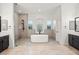 Luxury bathroom with a freestanding tub, walk-in shower, dual vanities, and decorative tile accents at 6004 Chessington Ave, Las Vegas, NV 89131