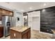 Kitchen with island, stainless steel refrigerator, pantry, and dark wood plank accent wall at 7806 Sundial Peak St, Las Vegas, NV 89166