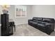 Cozy living room with plush gray carpeting, a black leather couch, piano, and a bright window at 7806 Sundial Peak St, Las Vegas, NV 89166