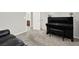 Spacious living room featuring plush gray carpeting, a black leather couch, a piano, and entry to bathroom at 7806 Sundial Peak St, Las Vegas, NV 89166