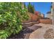 Landscaped backyard featuring pavers, mature trees, landscaping, and a low retaining wall at 7865 Solid Horn Ct, Las Vegas, NV 89149