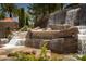 Scenic waterfall feature at Roma Hills community entrance. The landscape includes palm trees and lush foliage at 1800 Melfi Ct, Henderson, NV 89012